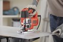 Oranje en zilveren Black+Decker decoupeerzaag met variabele snelheid, in gebruik op metaal.
