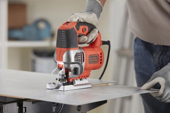Oranje en zilveren Black+Decker decoupeerzaag met variabele snelheid, in gebruik op metaal.