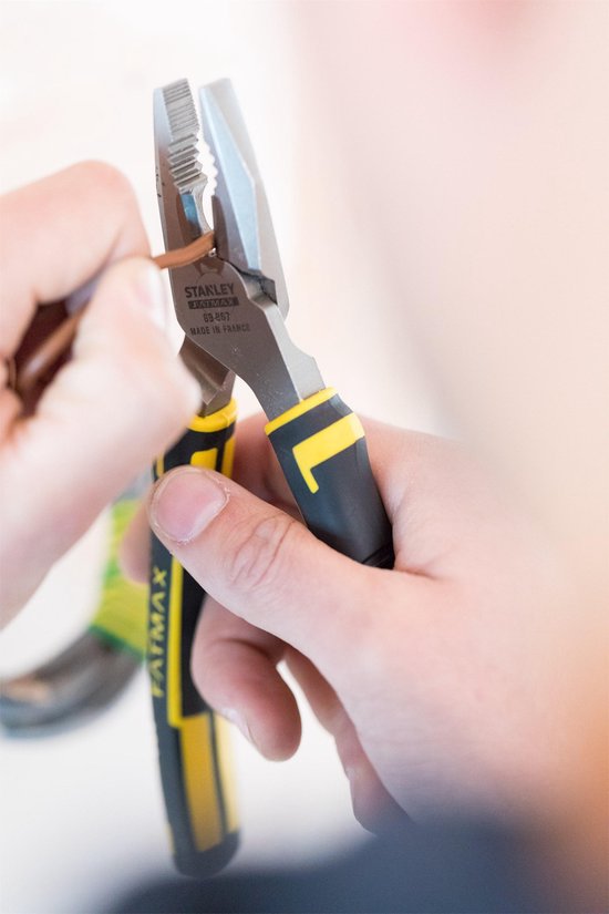 Handen gebruiken een Stanley FatMax combinatietang om een draad te strippen.