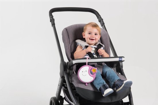 Baby in een kinderstoel met een roze muziekmobiel met maan en ster.