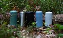 Vijf RETULP tumblers in groen, zilver, zwart, blauw en lichtgrijs in het bos.