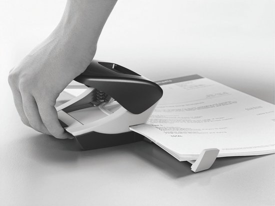 Hand gebruikt een perforator om in een stapel papier te perforeren.