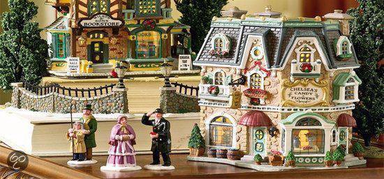 Gedetailleerde kerstdorpgebouwen met figuren en bomen.