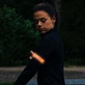 Vrouw met zwarte sportkleding met oranje oplichtende armband om haar arm, 's avonds in het bos.