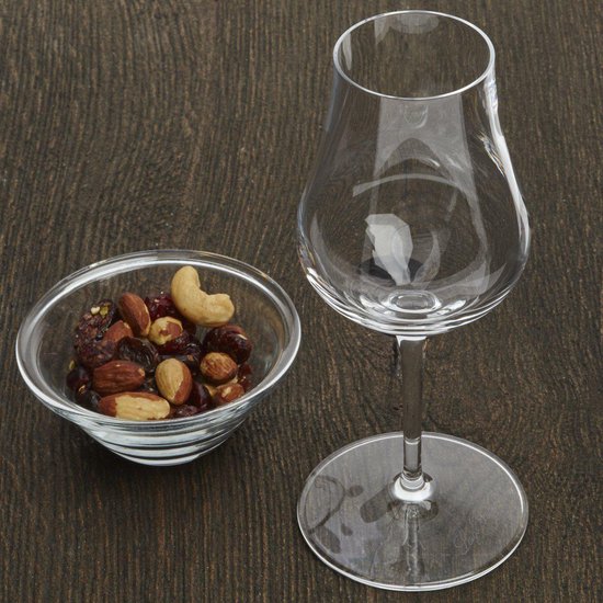 Glas met brede kelk, smalle opening, hoge steel, naast een schaaltje met noten en cranberries.