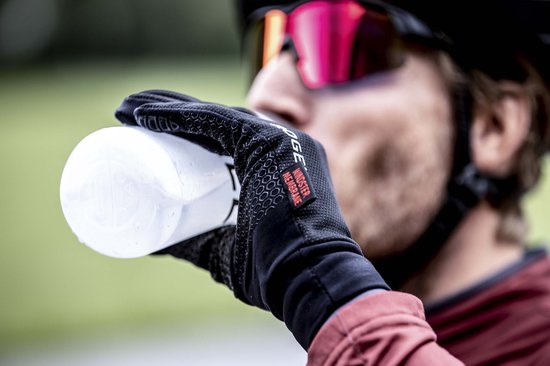 Zwarte Rogelli fietshandschoen met stippenpatroon, gedragen door een fietser die drinkt.