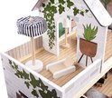 Poppenhuis met zonnebed, staande lamp met gestreepte kap en planten.