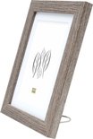 Cadre photo en bois gris sur pied, avec passe-partout blanc et dessin de feuilles.