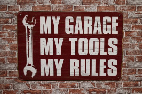 Metalen bord met de tekst 'MY GARAGE MY TOOLS MY RULES' en een steeksleutel, hangend tegen een bakstenen muur.