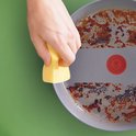 Main frottant avec une éponge jaune l'intérieur sale et brûlé d'une poêle avec Thermo-Signal.