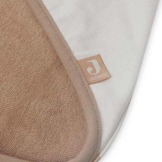 Détail d'une cape de bain blanc cassé avec intérieur beige en tissu éponge et bordure beige. Le logo Jollein est visible.