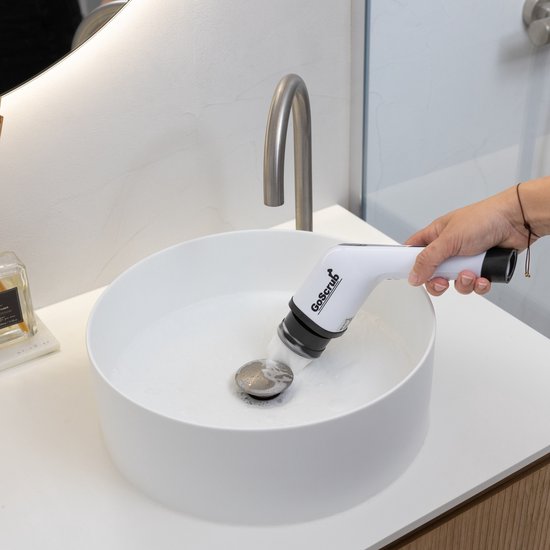 Hand gebruikt de witte elektrische schrobborstel om de wastafel schoon te maken.