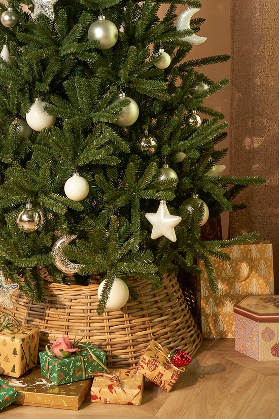 Onderkant van een gedecoreerde kunstkerstboom met mand, cadeaus, witte en zilveren ballen, sterren en manen.