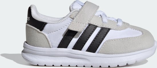 Zijaanzicht van een witte kindersneaker met grijze suède overlays, zwarte Adidas-strepen en klittenbandsluiting.