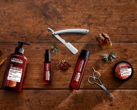 L'Oréal Men Expert BarberClub producten op een houten ondergrond. Met waakscheermes en schaar.