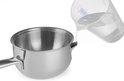 Water wordt uit een glazen maatbeker in een roestvrijstalen steelpan gegoten.