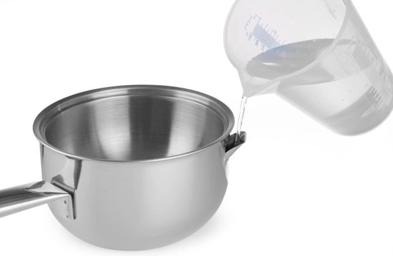 Water wordt uit een glazen maatbeker in een roestvrijstalen steelpan gegoten.