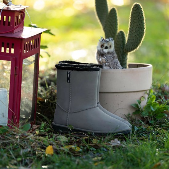 Grijze laarzen met zwarte teddy voering, naast een rode lantaarn en een cactus.