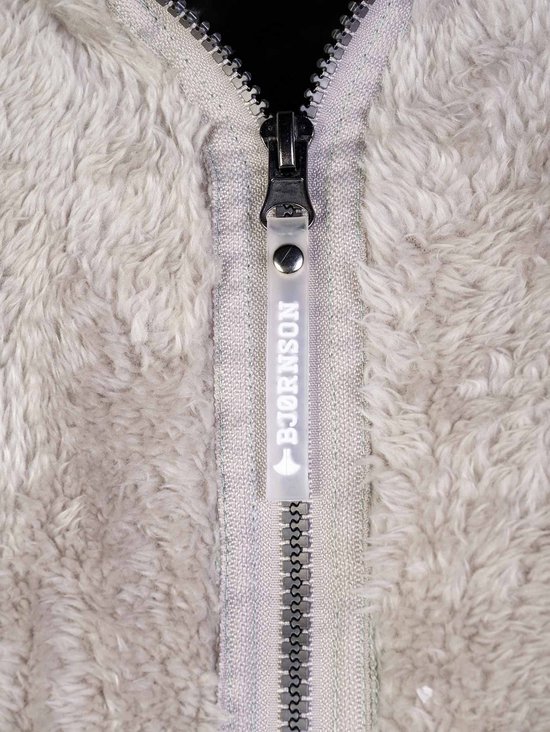 Detail van de ritssluiting met "BJØRNSON" label op een beige fleece bodywarmer.