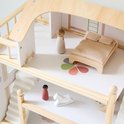 Detail van de middelste verdieping van het houten poppenhuis met speelgoedpoppetjes, bed en wipstoel.