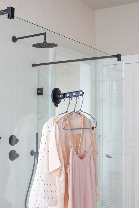 Zwarte inklapbare kledinghaak met zuignap hangt kleding op in een moderne douche.