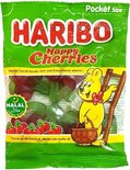 Haribo Happy Cherries zak met rode en groene kersvormige snoepjes. Een gele beer met een mandje staat naast een ladder.