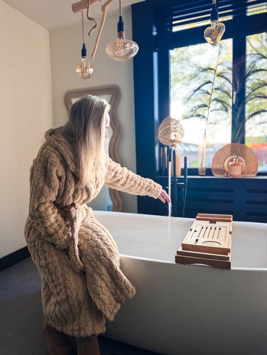 Lange beige badjas met capuchon van zacht fleece, bij een bad.