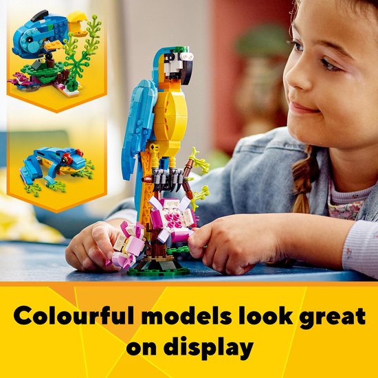Een LEGO papegaai op een tak met bloemen en een klein blauw visje en een kikker op de achtergrond.