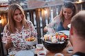 Vrolijke groep vrienden aan tafel met de zwarte Barbecook tafelgrill, waarop spiesjes met vlees en groenten liggen.