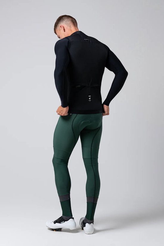 Achterkant van een man die een zwart fietsshirt met lange mouwen en donkergroene fietsbroek draagt.
