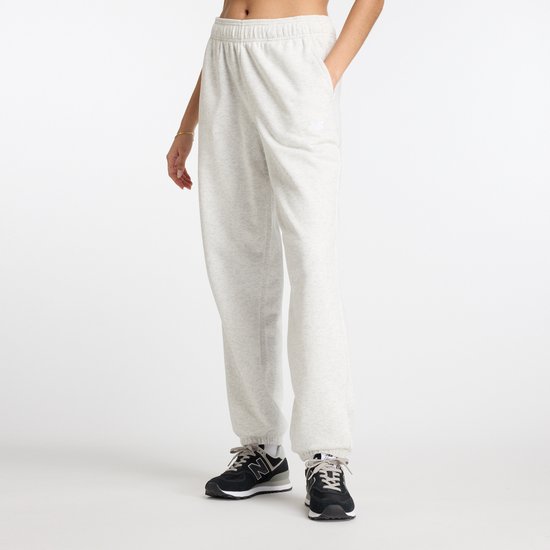 Een model draagt een lichtgrijze joggingbroek van french terry met een elastische tailleband en trekkoord. Het geborduurde logo is zichtbaar op de heup.
