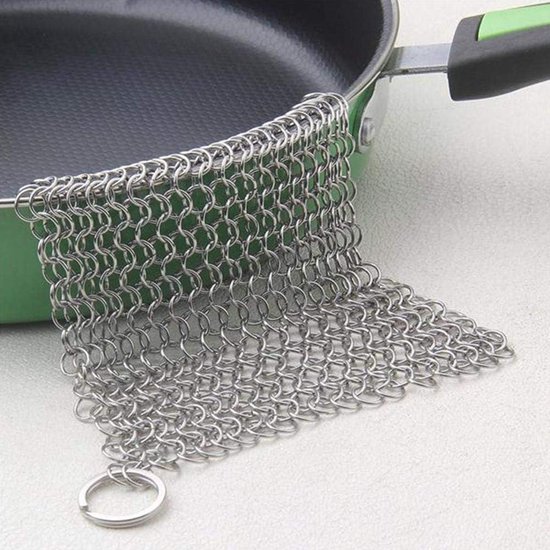 RVS ketting scrubber met ring ligt op een groene koekenpan.