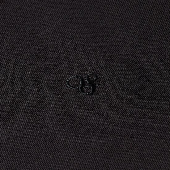 Detail van een zwart poloshirt met een geborduurd ton sur ton logo.