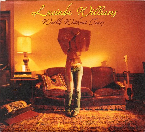 Lucinda Williams World Without Tears albumhoes met vrouw in spijkerbroek en bruine top voor een bank.
