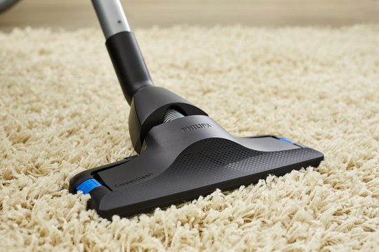 De mondstuk van een Philips stofzuiger op een beige tapijt.