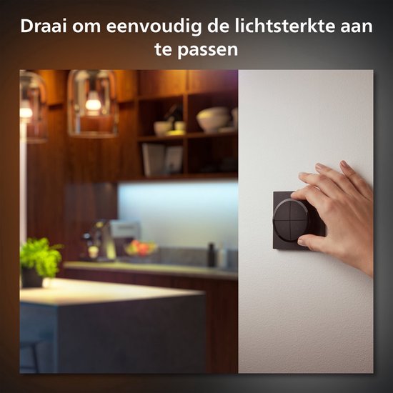Een hand draait aan de zwarte Philips Hue draaischakelaar om de lichtsterkte aan te passen.