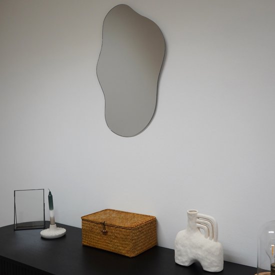 Une boîte de rangement en rotin avec couvercle est posée sur une commode noire à côté d'un vase et d'un chandelier.