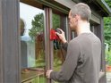 Man schuurt een houten kozijn met een rode Einhell schuurmachine met stofzak.