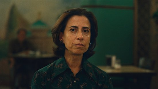 Close-up van een vrouw met bruin haar en een donkere, bedrukte blouse, met een diepe blik.