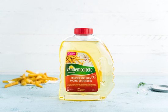 2L fles Vandemoortele frituurolie met rode dop. De gele vloeistof bevat de tekst "Minder Geuren Mins Odeurs" en "New Pack Design". Naast de fles liggen frietjes.