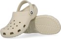 Crème Crocs klomp met klittenband en "Crocs" logo, de andere klomp ligt op de zool.