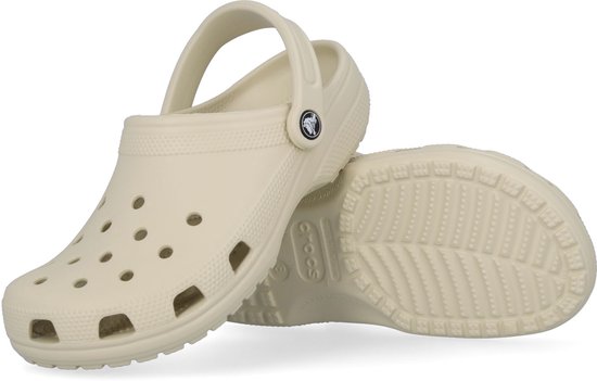 Crème Crocs klomp met klittenband en "Crocs" logo, de andere klomp ligt op de zool.