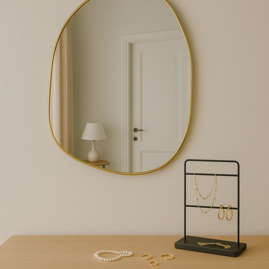 Gouden spiegel in organische vorm, reflecteert een deur en een lamp.