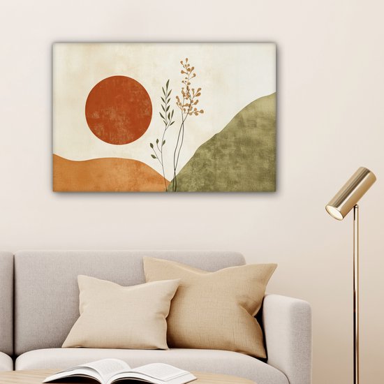 Abstract schilderij met oranje zon, takken en groene heuvels, boven een bank met gouden lamp.