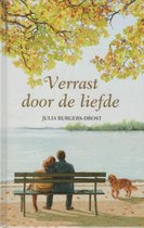Boek "Verrast door de liefde". Een stel op een bankje kijkt uit over het water, met een hondje ernaast.