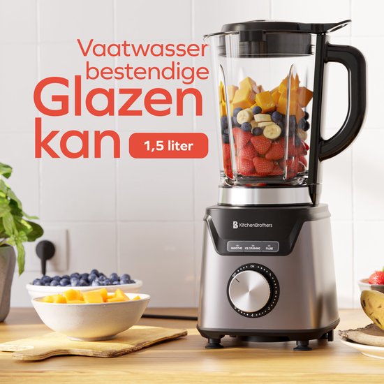 Glazen blenderkan 1,5L met fruit en bessen, naast kommetjes met fruit en bessen op houten aanrecht.