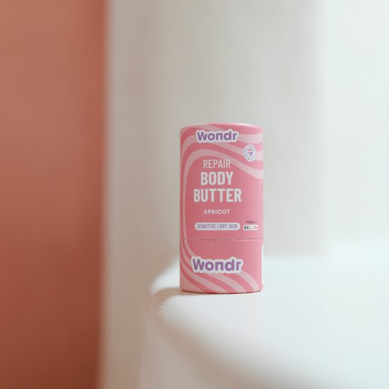 Bâton de beurre corporel rose avec des vagues blanches. Wondr Repair Body Butter, Abricot.