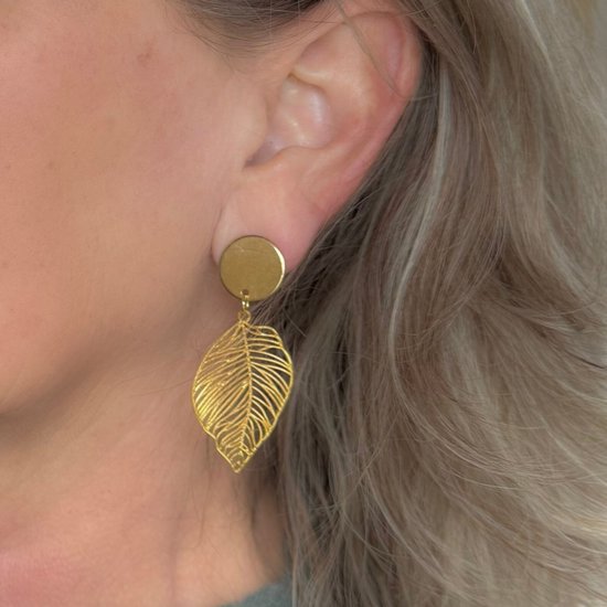 Model met gouden clip-oorbellen met ronde top en lang, opengewerkt palmblad.
