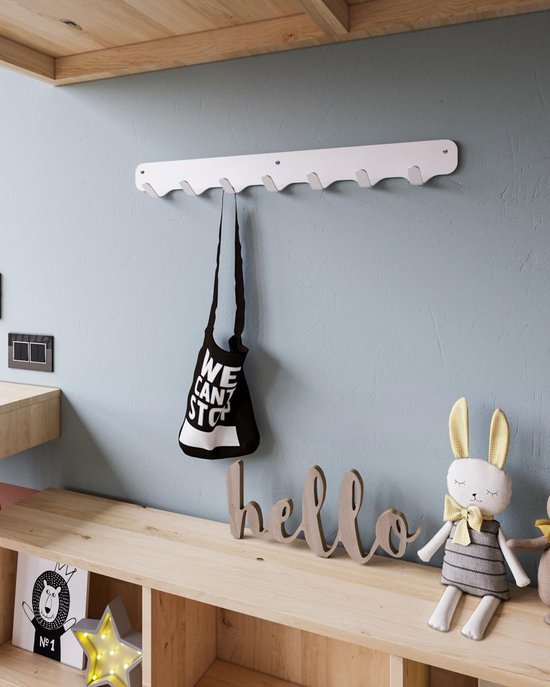 Witte stalen kapstok met 7 haken, bevestigd aan een blauwe muur boven een houten plank. Een zwarte tas hangt aan de middelste haak.