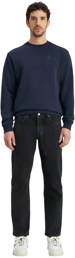 Man met donkerblauwe sweater, staand.